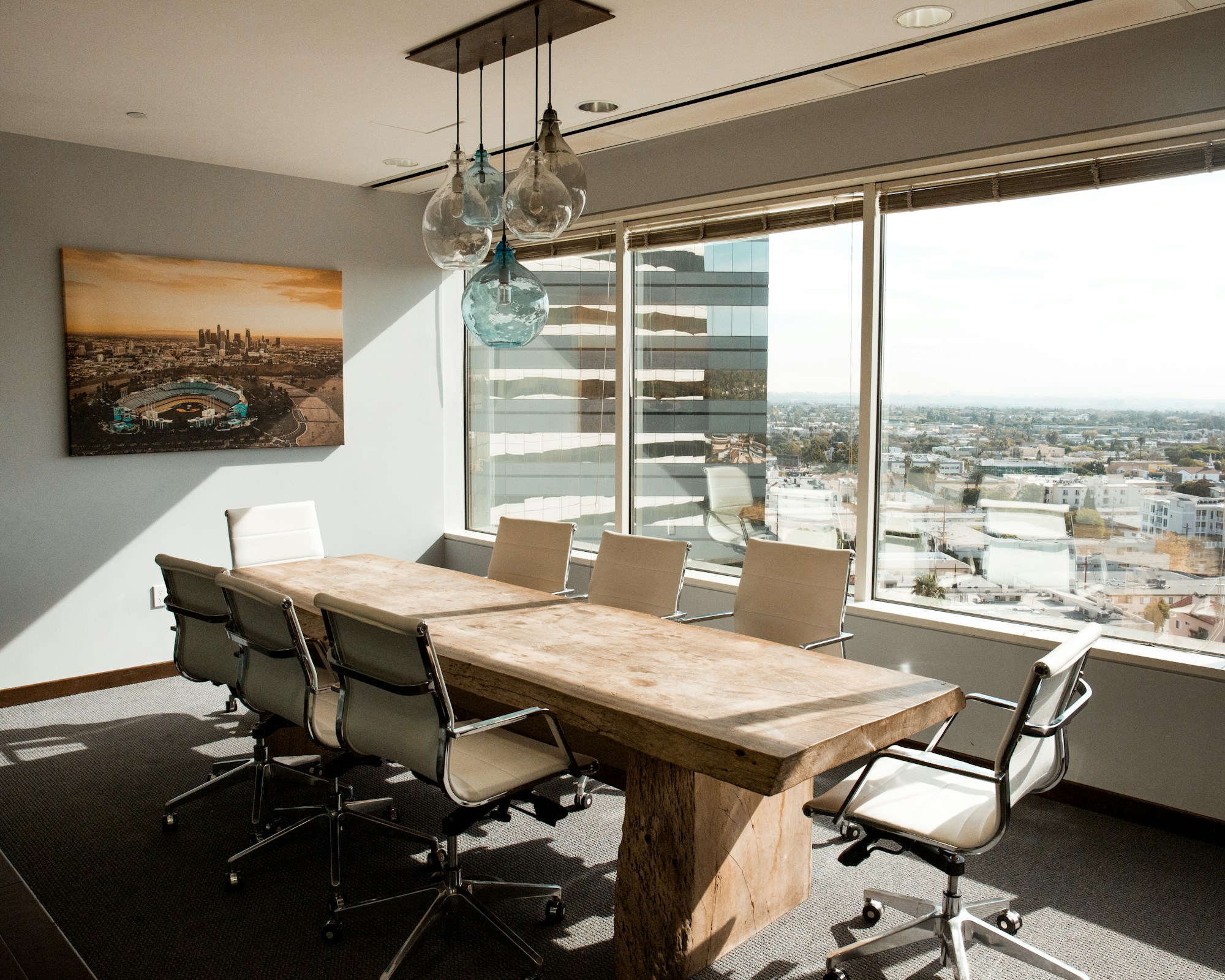 A beige wooden conference table in a daylit boardroom.