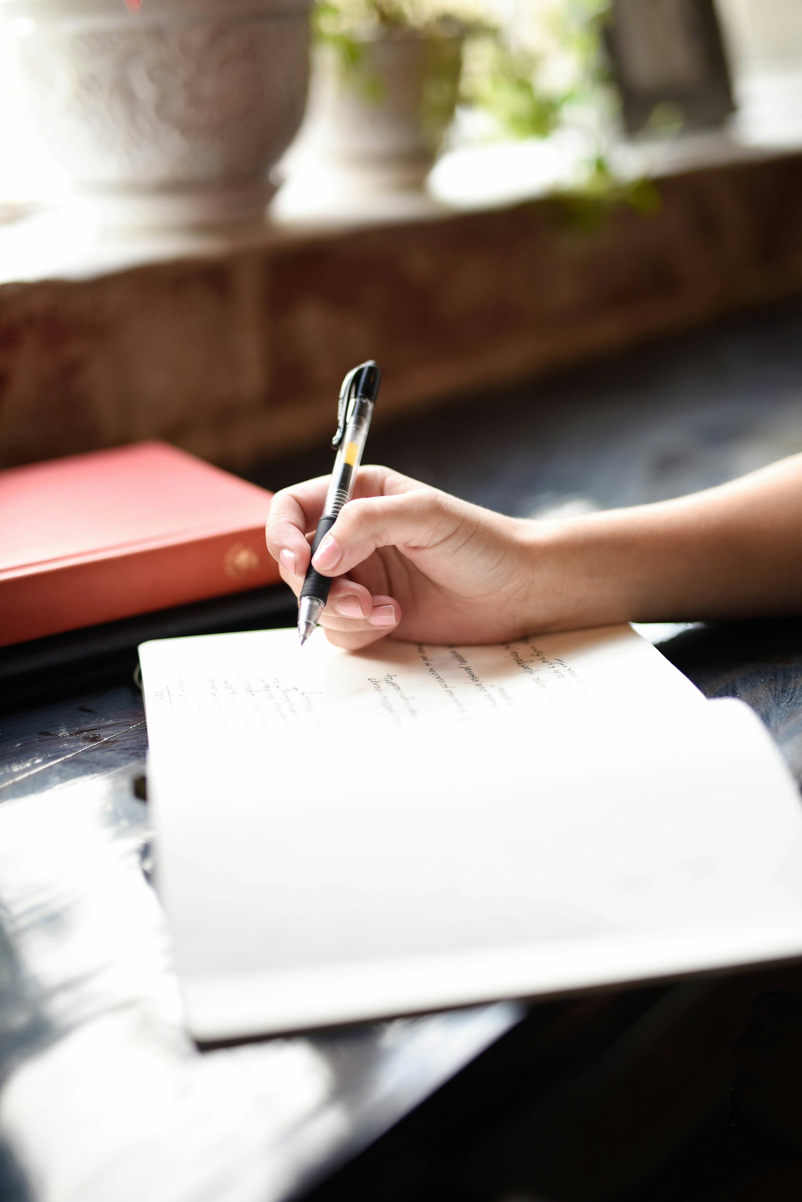 A hand writing on a piece of paper with a pen.